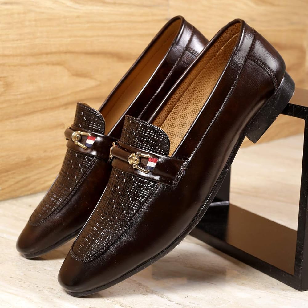Brown leather loafers with decorative buckles on a wooden surface