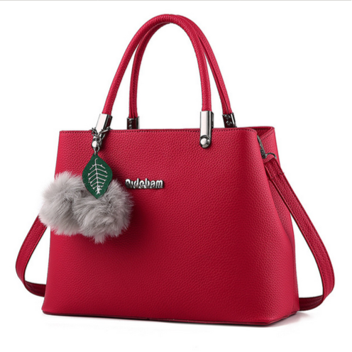 Red handbag with a gray pom-pom and brand name tag on a white background